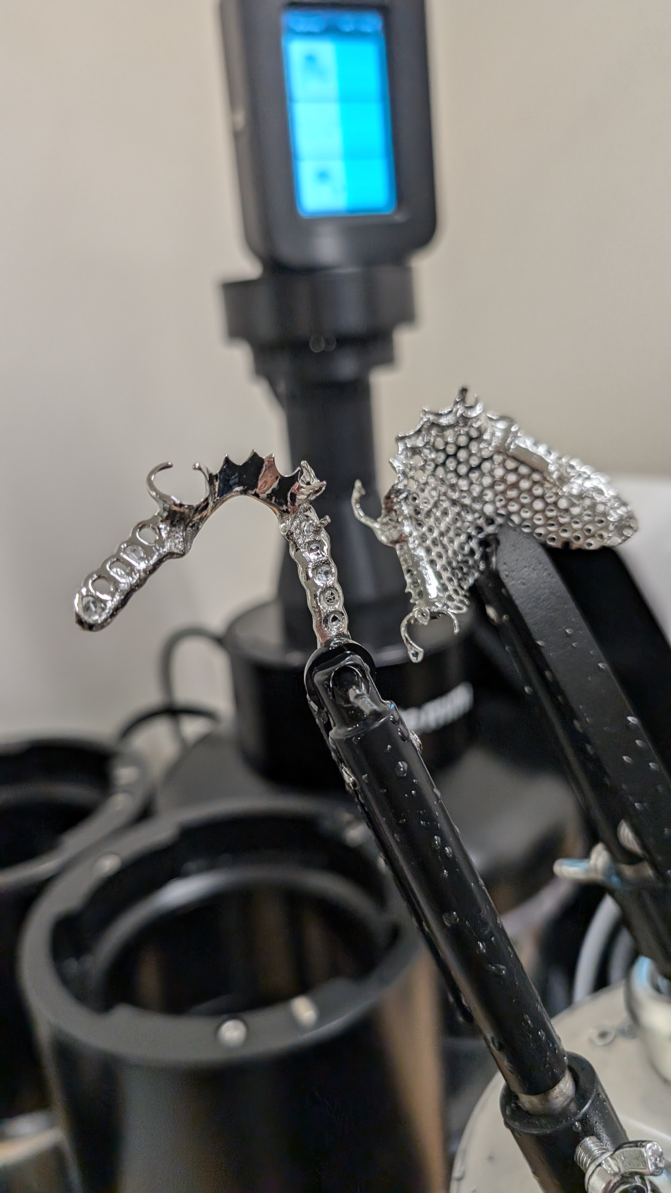 Framework held in tongs during DLyte electropolishing